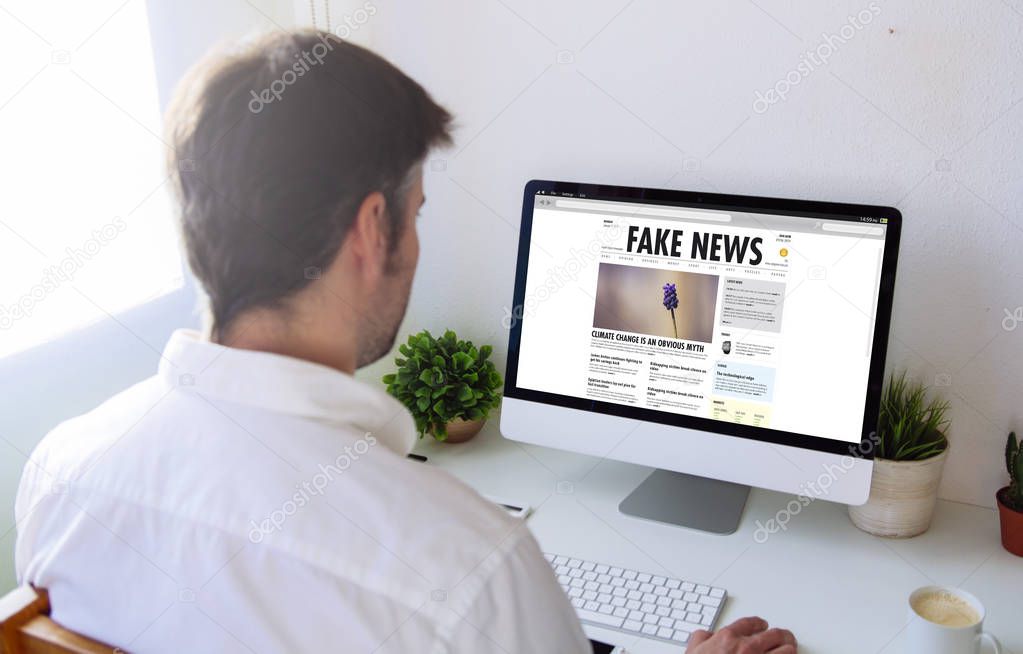 man using desktop pc, fake news website on screen