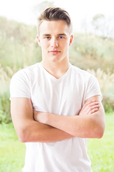 portrait of young man with arms crossed against nature background