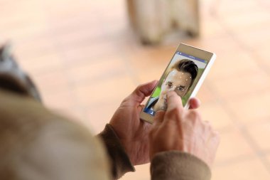 man touching screen of smartphone to use facial recognition clipart