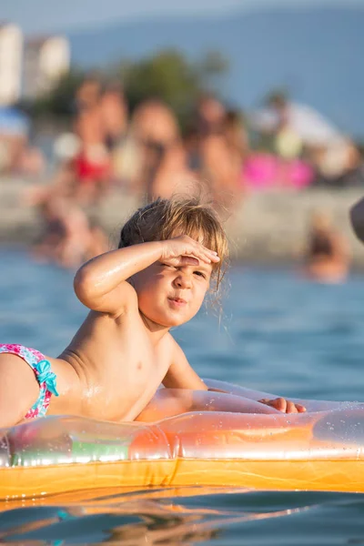 Ребенок на надувном матрасе, наслаждаясь солнцем и морем — стоковое фото