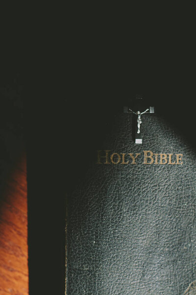 a bible book and cross in the sunlight.