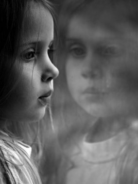 küçük bir kız bir pencereden dışarı bakarak