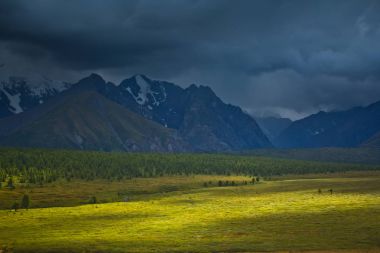 Güzel görünüm kar dağlar ve güneş ışığı ve fırtına gökyüzü ile yeşil alan