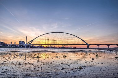 New city, Nijmegen, Hollanda Waal nehrinde bir ıslak kum plajındaki gece karanlığında yansıtan De Oversteek (Crossing) köprü