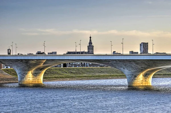 The extended Waalbridge across the new channel of the river Waal with the church and other buildings of the city Nijmegen, The Netherlands in the background