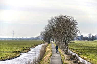 Poldernear Leiden, Hollanda, kışın soğuk bir gününde dar bir yol üzerinde yalnız motorcu