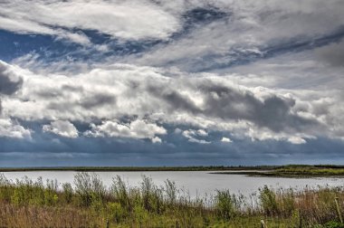 Güneyden üzerinde küçük göller ve düşük bitki örtüsü ile düz bir manzara doğa Adası, Tiengemeten üzerinde Hollanda haddeleme karanlık yağmur bulutları