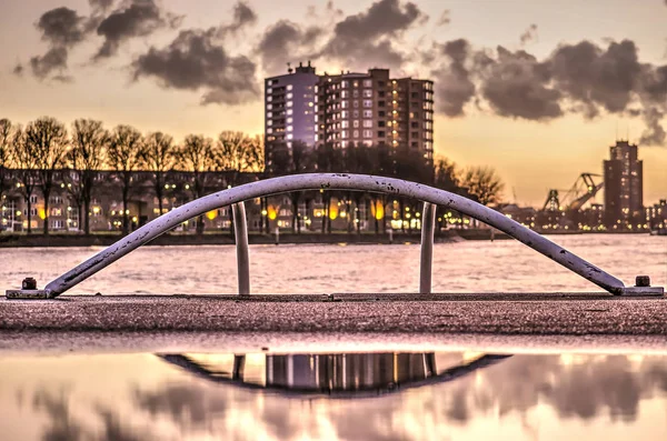 Arched top end of an emergency ladder at the quay of wilhelmina Pier in Rotterdam shortly after sunset