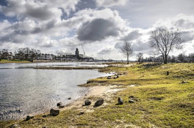 Sandy beach Deventer, Hollanda içinde belgili tanımlık geçmiş şehir manzarası ile Ijssel Nehri boyunca dağınık kayalar ile