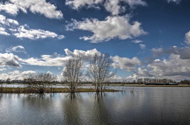 Scatered bulutlar Nehri Ijssel Deventer, Hollanda ve bazı tis ile mavi gökyüzü kanalları yan