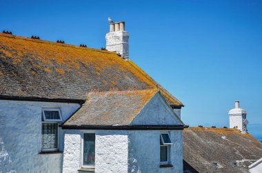 Kara'nın sonunda, Cornwall, Büyük Britanya, 27 Mayıs 2014: beyaz sıva duvar ve kayrak bir çatı ile geleneksel ev kısmen kapsanan mavi gökyüzü karşı kırmızımsı liken ile