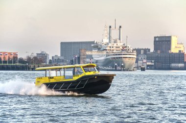 Rotterdam, Hollanda, 3 Aralık 2019: Nieuwe Maas nehri üzerinde tarihi yolcu gemisi Ss Rotterdam ve Maashaven limanı ile hızlı sarı ve siyah su taksisi