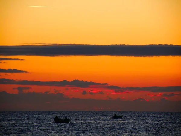 Blood orange sunrise on the sea with a fishing boat