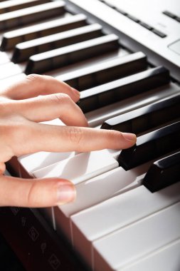 Elektronik sentezleyici piyano tuşlarıyla oynayan çocuk elleri yakından görülüyor. Müzik dükkanları, posterler, reklam broşürleri, kartvizitler, web sunumları için dikey fotoğraf hazır. Metin için yer