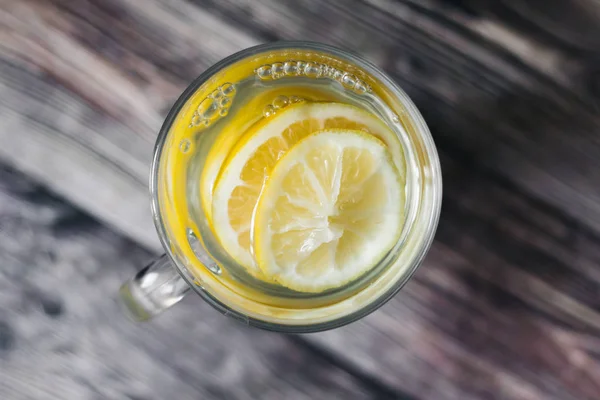 Tea or homemade lemonade with lemon on a rustic wooden background. vitamins for health for colds — Stock Photo, Image