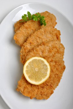 ekmekli balık biftek bir plaka üzerinde organik limon ile
