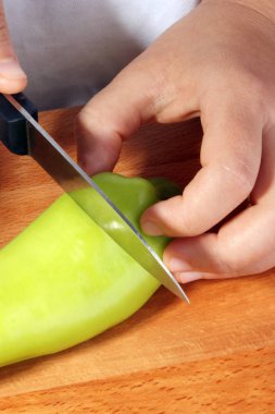 bir organik kırmızı biber, iki el ve bıçakla kesmek