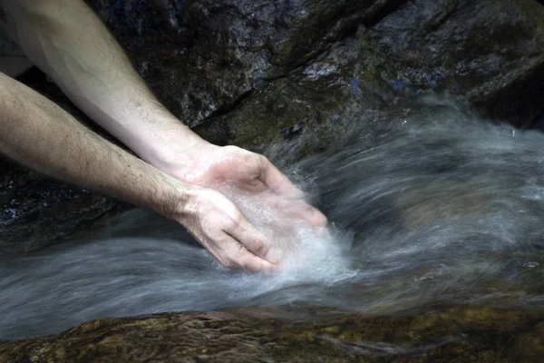 person Washing Hands In A Stream