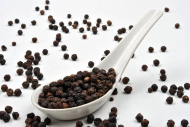 Beyaz Seramik kaşık üzerinde siyah organik biber  