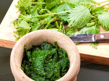 Pişmiş ve pişmemiş Nettles ahşap oyun tahtası ve rustik bir havan topu
