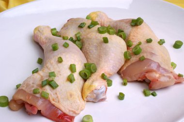 çiğ tavuk uyluk adet beyaz tabakta yeşil soğan ile yakın çekim 