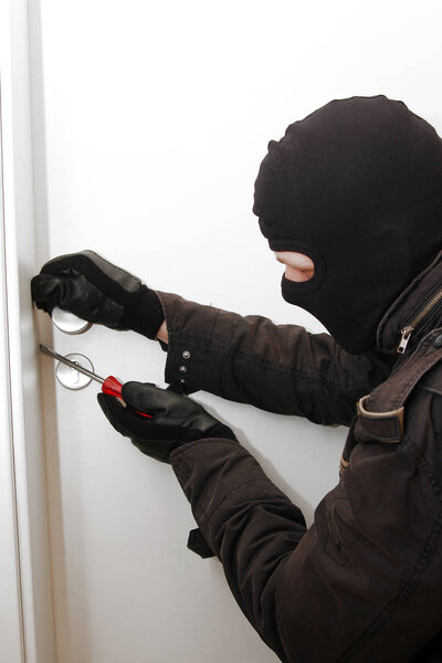 Грабитель в черной одежде в балаклаве на голове
