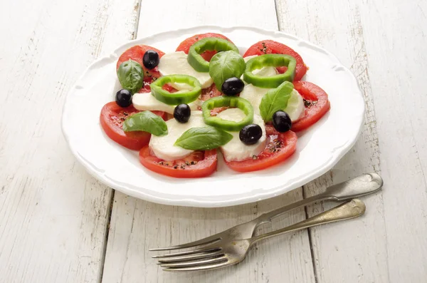 Summer Salad Make From Tomato, Mozzarella, Black Olive, Green Chili And Basil On A White Plate