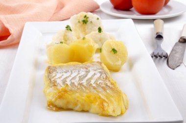 COD haşlanmış patates, eritilmiş tereyağı, karnabahar ve maydanoz bir plaka üzerinde füme