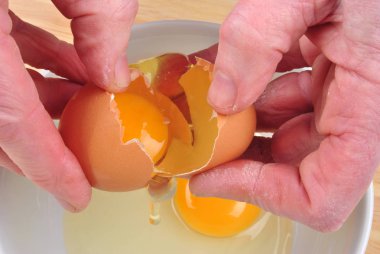 close up on hands, person braking shell of egg  clipart