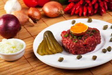biftek tartar beyaz tabakta açılan yumurta ile yakın çekim 