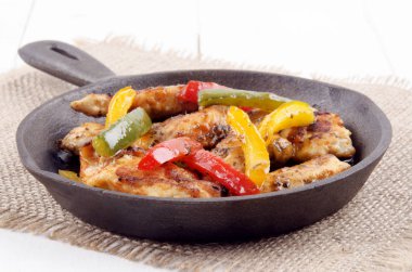 ızgara tavuk fileto şeritler ile dökme demir tavada jüt üzerinde renkli biber