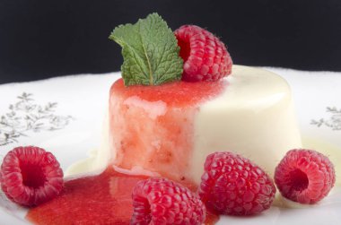 Ahududu Panna Cotta ile meyve sosu ve nane bir plaka üzerinde