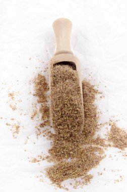 Organik keten tohumu ve beyaz kağıt üzerinde ahşap kürek soğuk öğütülmüş