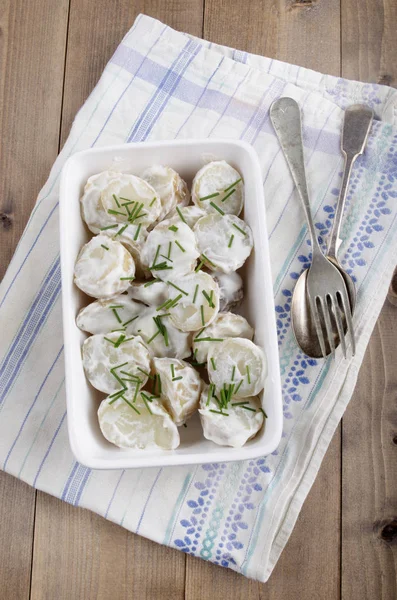 Creme Fraiche ve beyaz bir kase Chives ile bebek patates pişmiş
