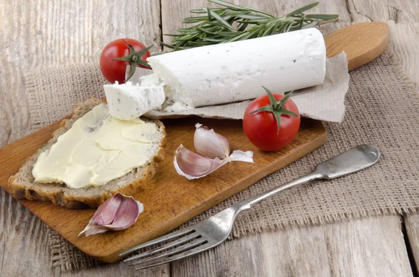 wooden board with bread and soft goat cheese with tomatoes