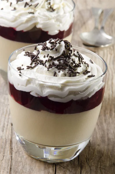 バター スコッチ 赤い果実のゼリーとデザートは素朴な木の上のガラスのクリームとチョコレートを振りかけるをホイップ クリーム — ストック写真