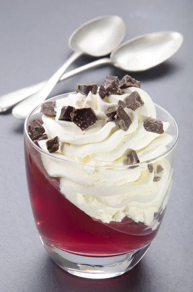 グラスの中のホイップ クリームと壊れたチョコレートとラズベリーのゼリー — ストック写真