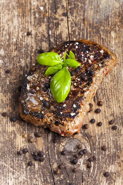 Gegrilltes Steak Mit Schwarzen Pfefferkörnern Und Basilikumblättern Auf Holztisch Nahaufnahme — Stockfoto