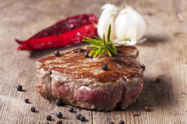 Gegrilltes Steak Mit Schwarzen Pfefferkörnern Und Rosmarin Auf Holztisch Nahaufnahme — Stockfoto