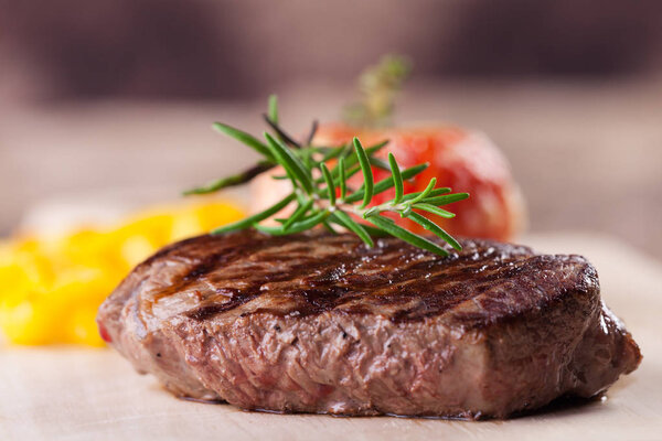 Grilled steak with rosemary on wooden table, close-up