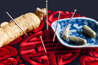 Akupunktur iğneleri, ginseng kökü ve bitkisel haplar.