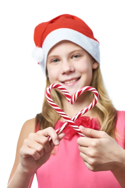 Ragazza in berretto rosso con bastoncini di zucchero natalizio come cuore isolato — Foto Stock