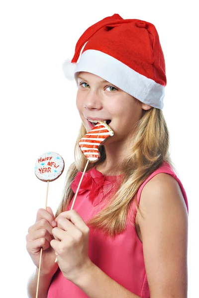 Happy teen girl in red cap eating Christmas cookie isolated — Stock Photo, Image