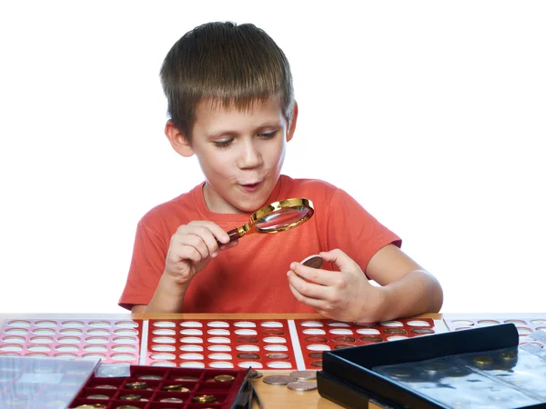 Boy examines coin through magnifying glass — Stockfoto