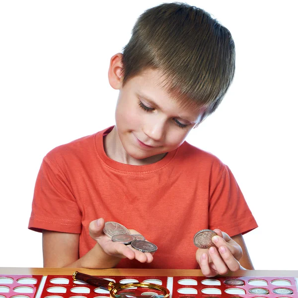 Boy examina las monedas de su colección aislada — Foto de Stock