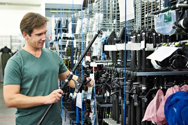 Mann wählt Angelrute im Geschäft — Stockfoto