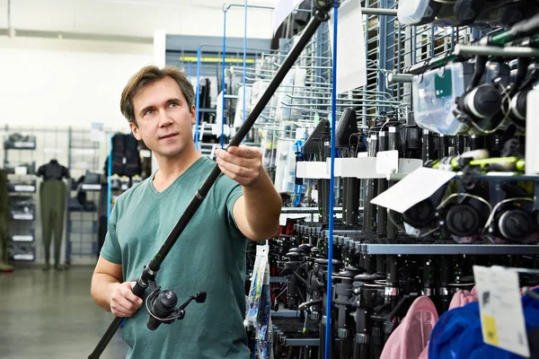 Mann wählt Angelrute im Geschäft — Stockfoto