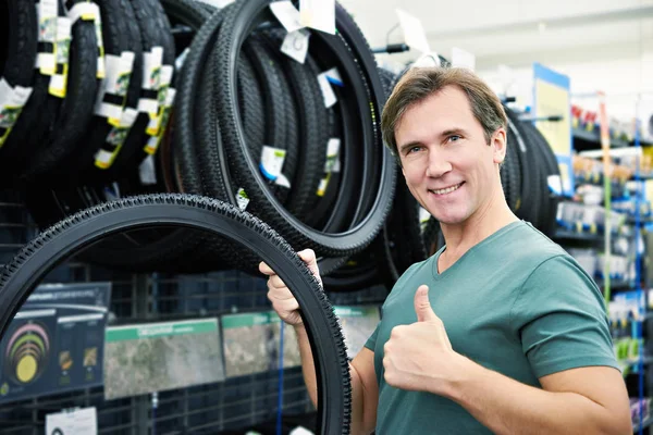 Felice uomo sceglie pneumatico per bici in negozio di sport — Foto Stock