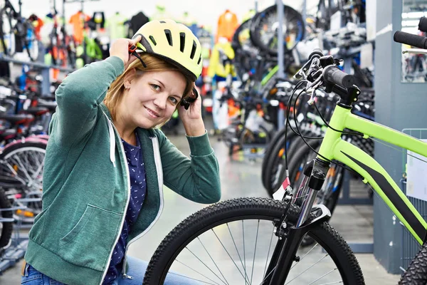 Mujer feliz tratando de casco para el ciclismo en la tienda —  Fotos de Stock