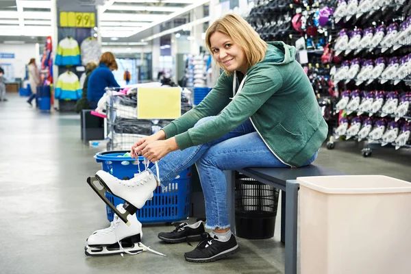 Gelukkige vrouw probeert op figuur klapschaatsen in sportzaak — Stockfoto